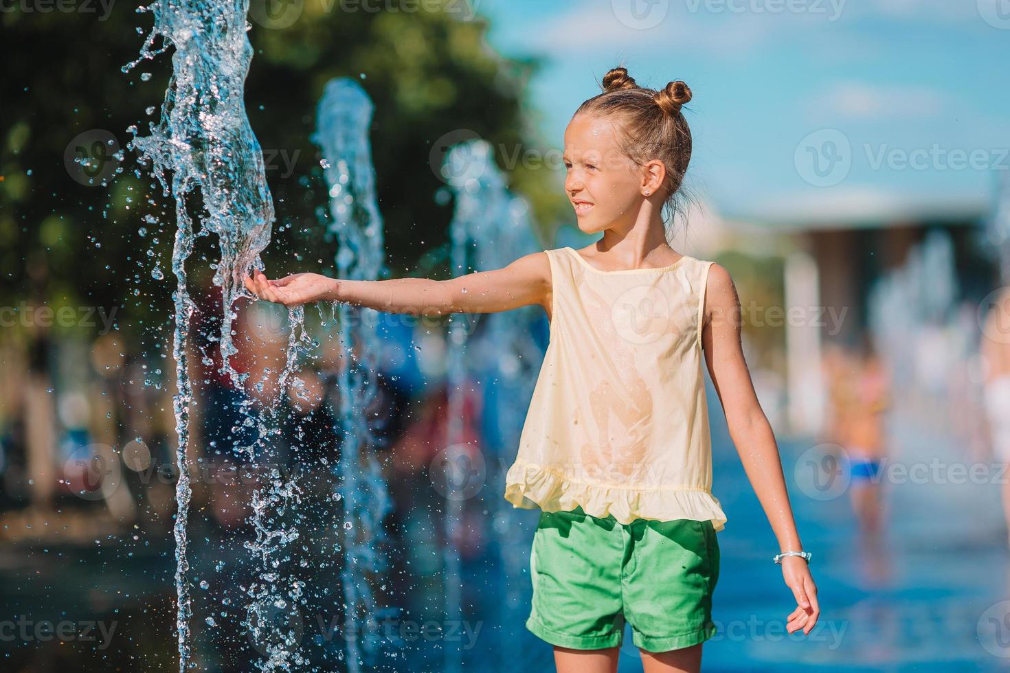 Kleines entzückendes Mädchen hat Spaß im Straßenbrunnen an heißen sonnigen Tagen foto