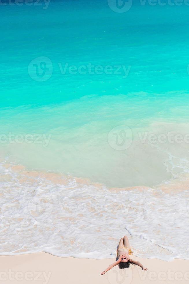 junge frau genießt die sonne beim sonnenbaden am perfekten türkisfarbenen ozean foto