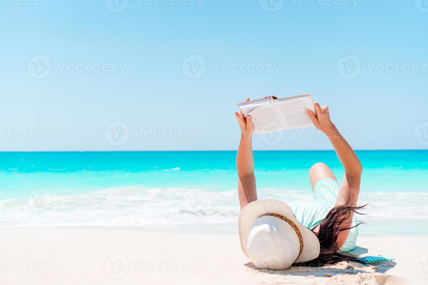 Lesebuch der jungen Frau während des tropischen weißen Strandes foto