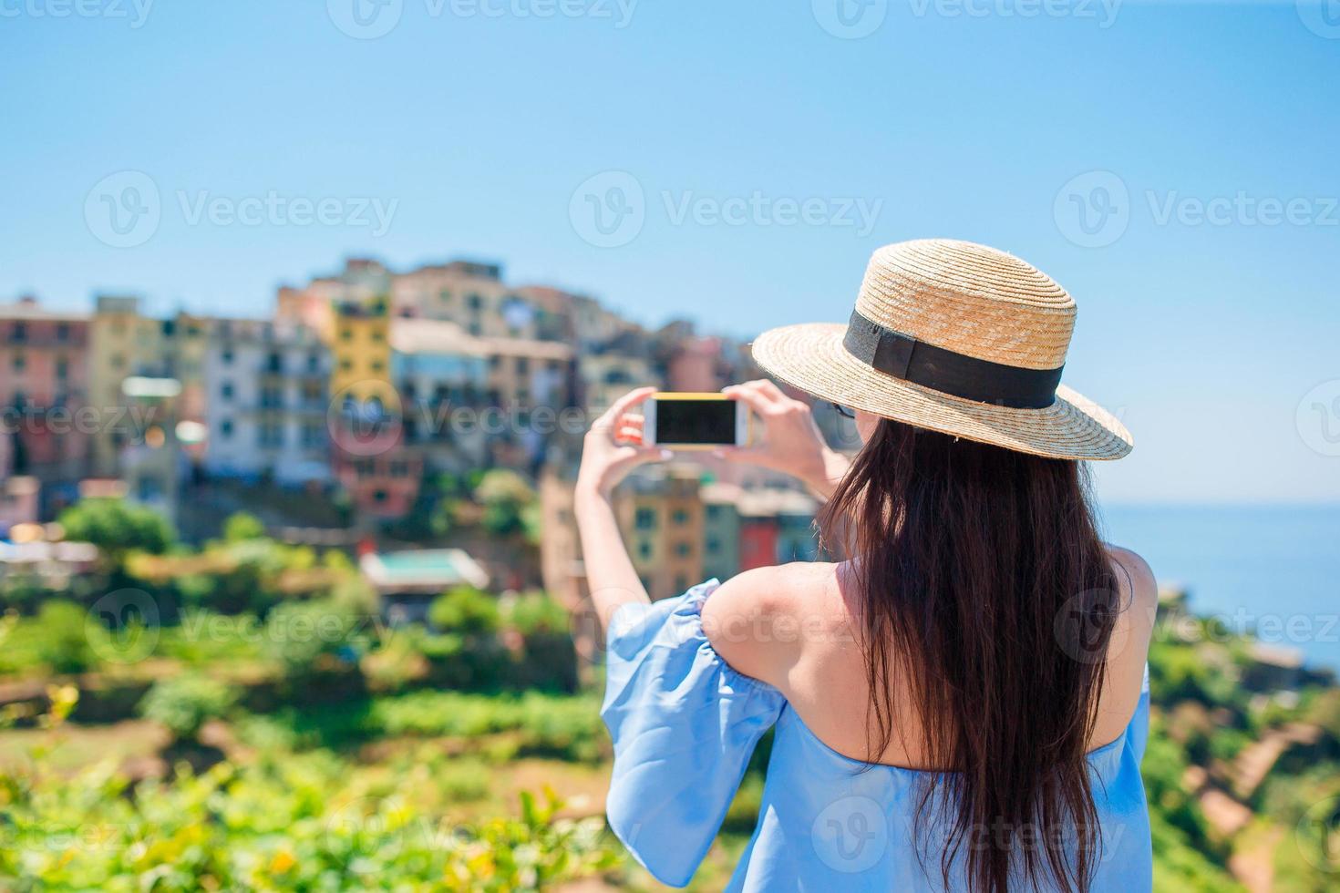 junge frau macht ein foto von der schönen aussicht auf das alte dorf in cinque terre, ligurien, italien. europäisch italienischer urlaub.