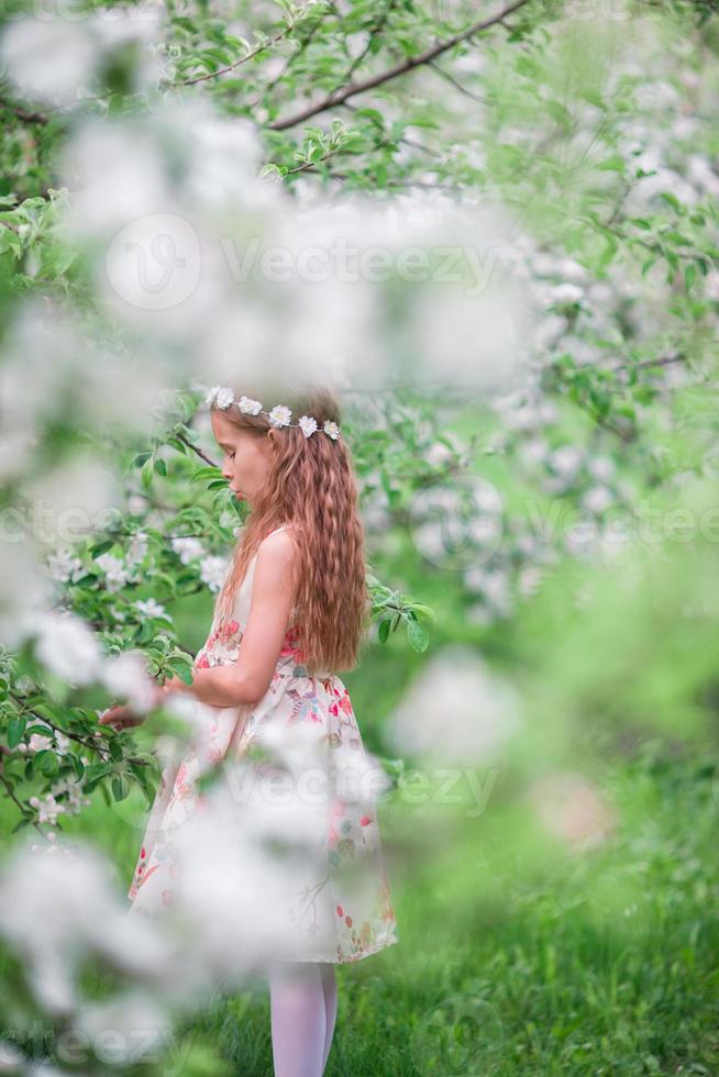 kleines süßes Mädchen im blühenden Kirschgarten im Freien foto