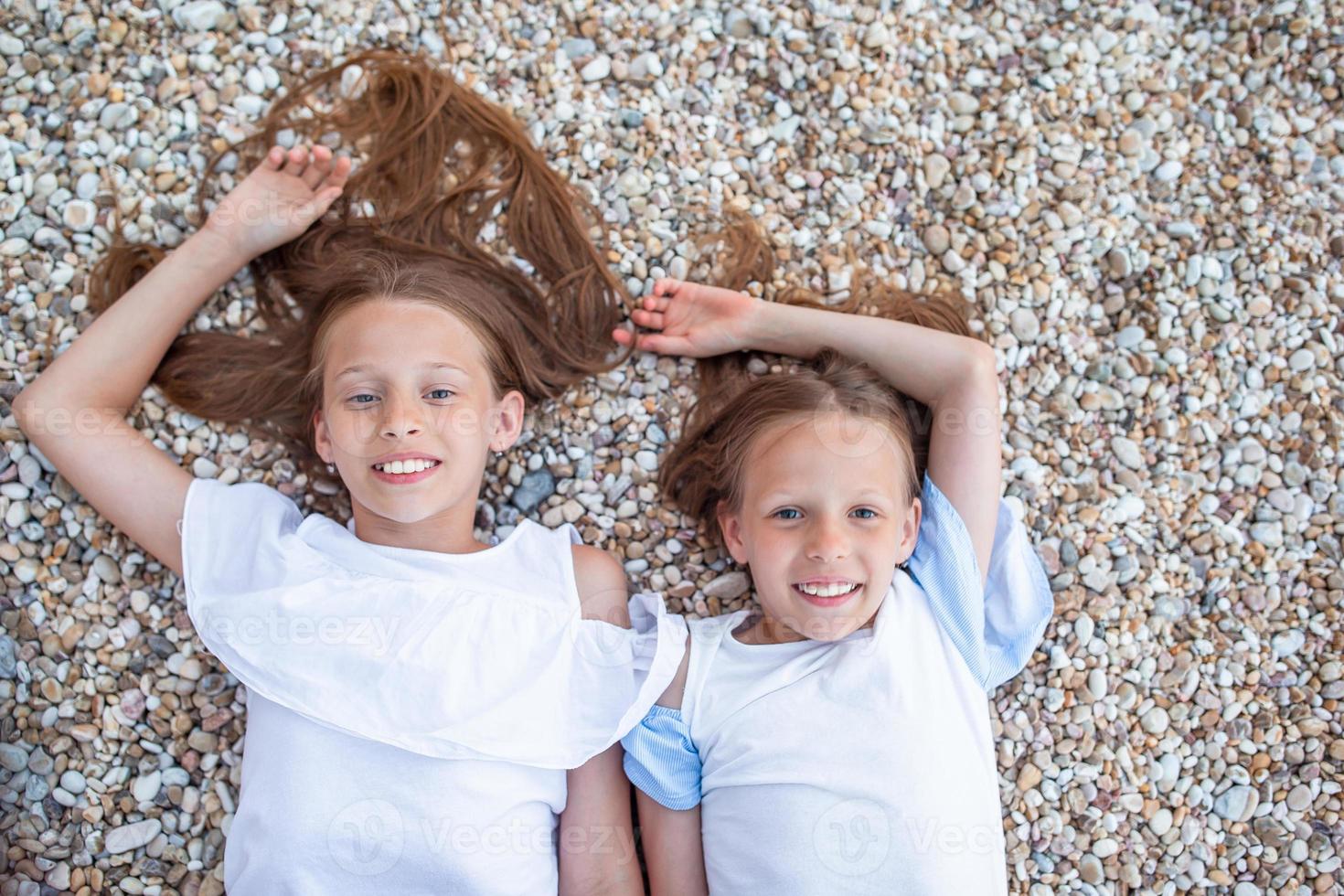 Kleine Mädchen, die sich während der Sommerferien am tropischen Strand amüsieren foto