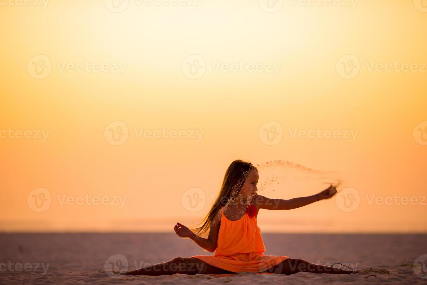 Silhouette eines sportlichen kleinen Mädchens am weißen Strand bei Sonnenuntergang foto