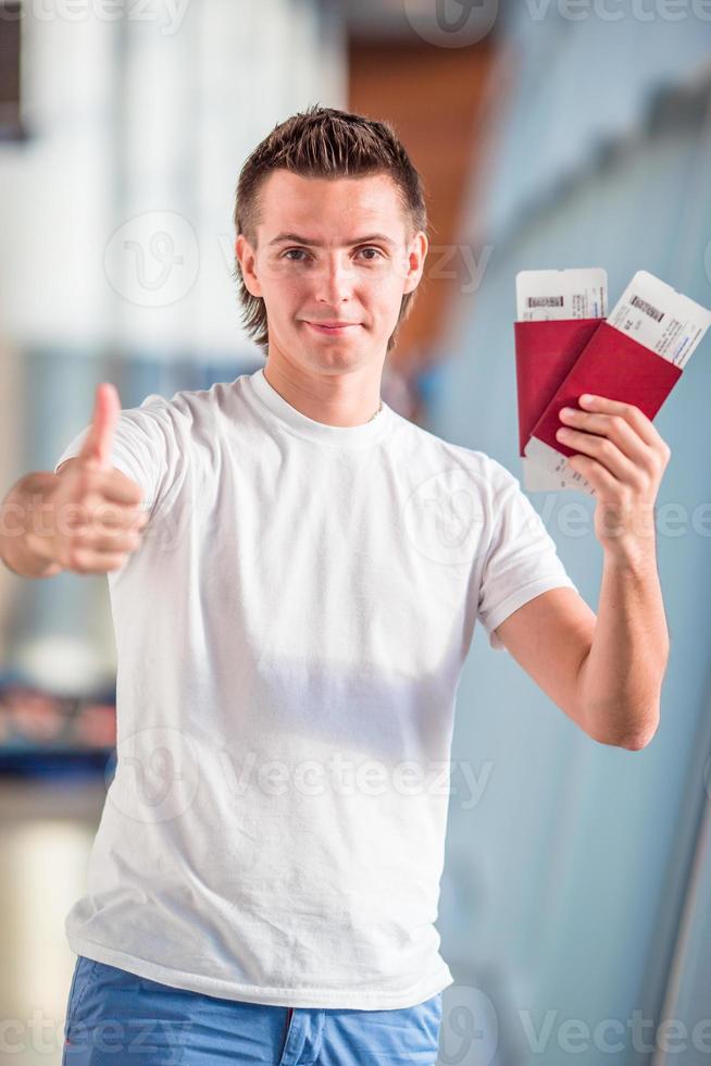 junger Mann mit Pässen und Bordkarten im Flughafen foto