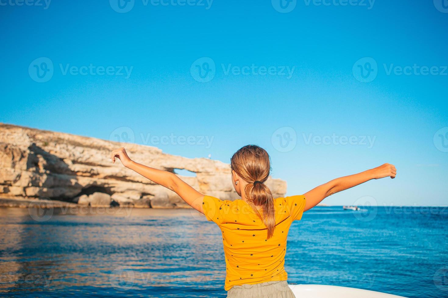 kleines Mädchen, das auf dem Boot im klaren offenen Meer segelt foto