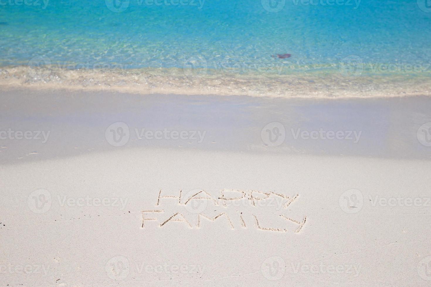 glückliche Familie geschrieben am weißen Sand des tropischen Strandes foto