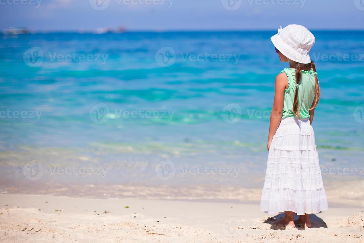 entzückendes kleines Mädchen, das auf tropischem weißem Strand geht foto