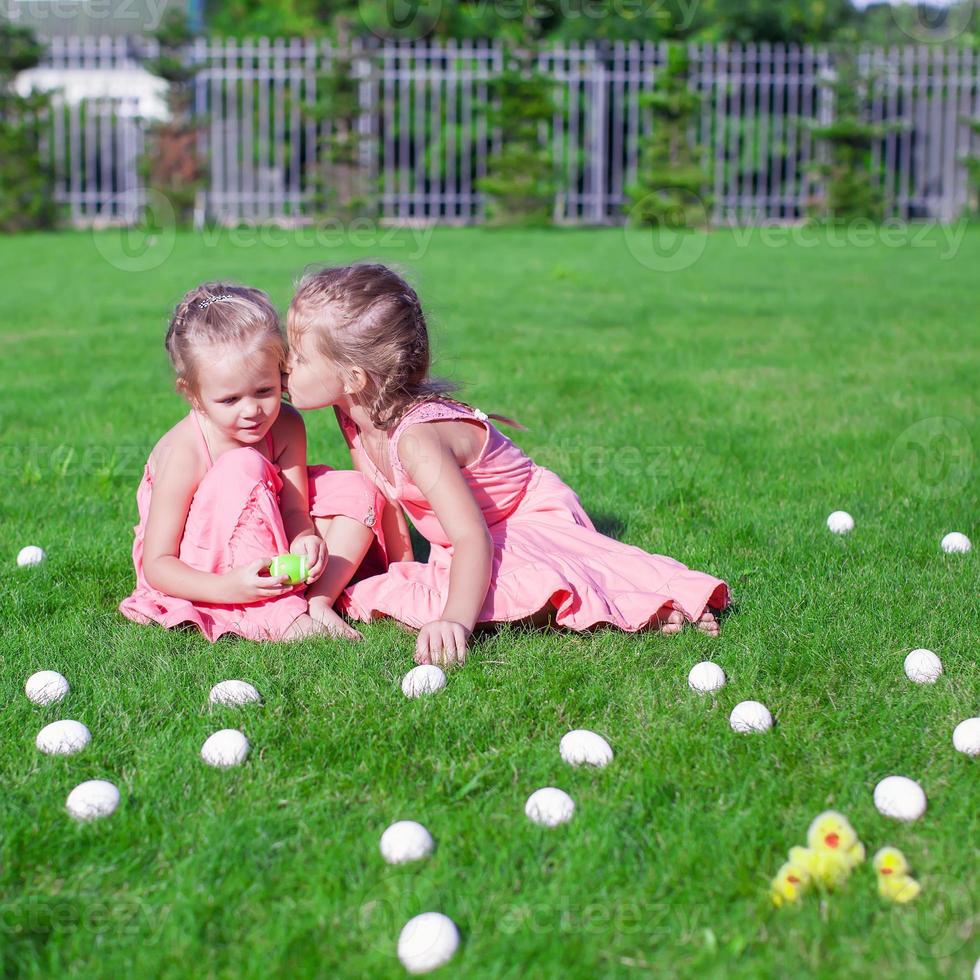 Entzückende kleine Mädchen, die sich mit Ostereiern auf grünem Gras amüsieren foto