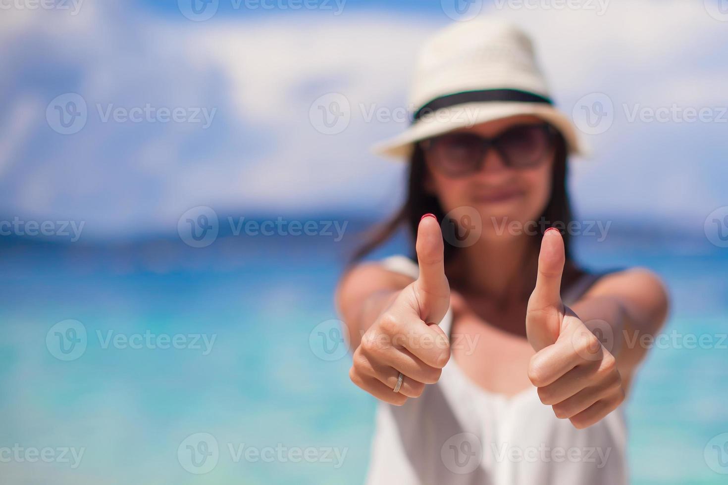 junge schöne Frau zeigt Daumen nach oben am Strand foto