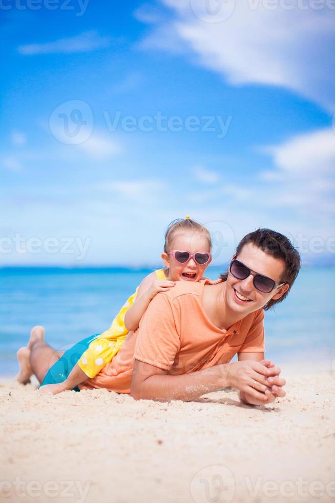 glücklicher Vater und entzückende kleine Tochter am Strand foto
