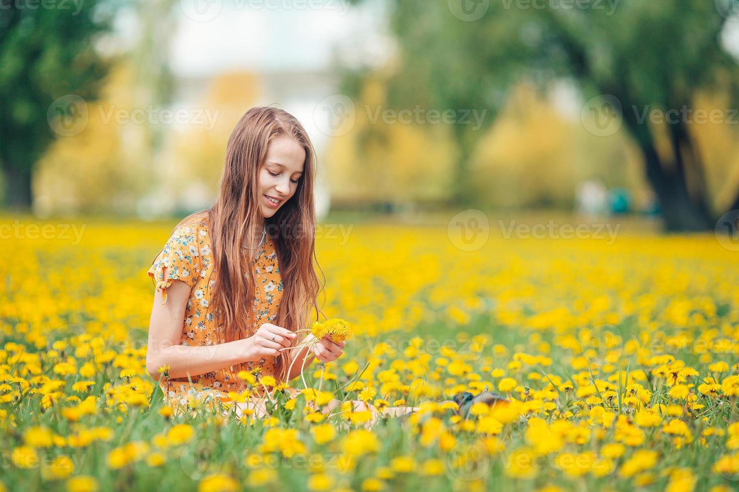 Kleines blondes Mädchen pflücken Blumen auf einer Wiese voller gelber Löwenzahn foto