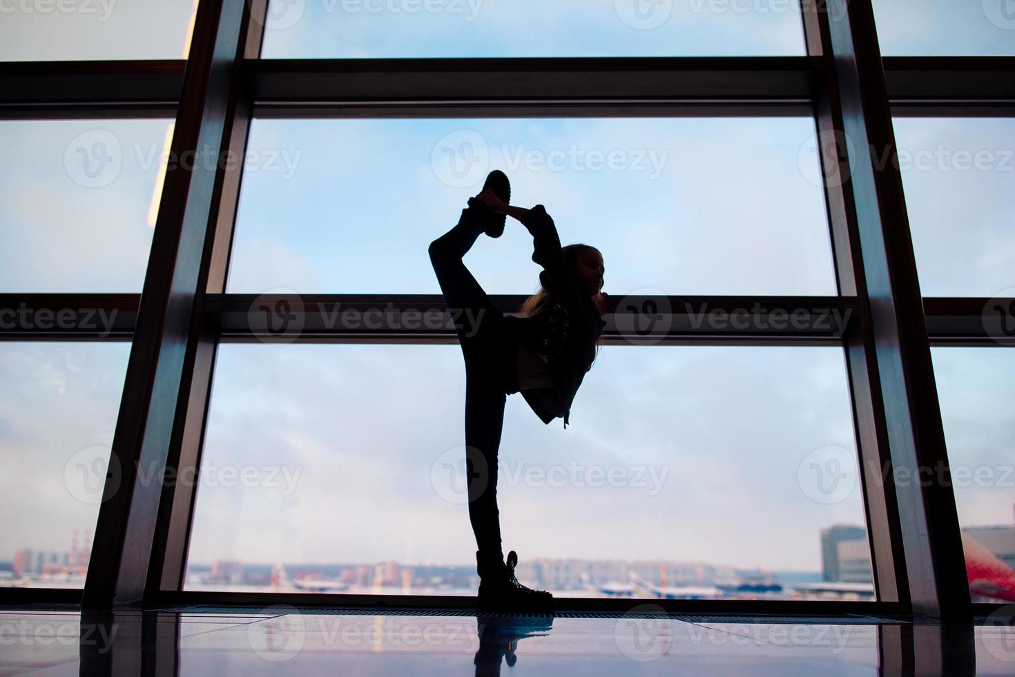 kleines Mädchen im Flughafen in der Nähe des großen Fensters, während es auf das Boarding wartet foto