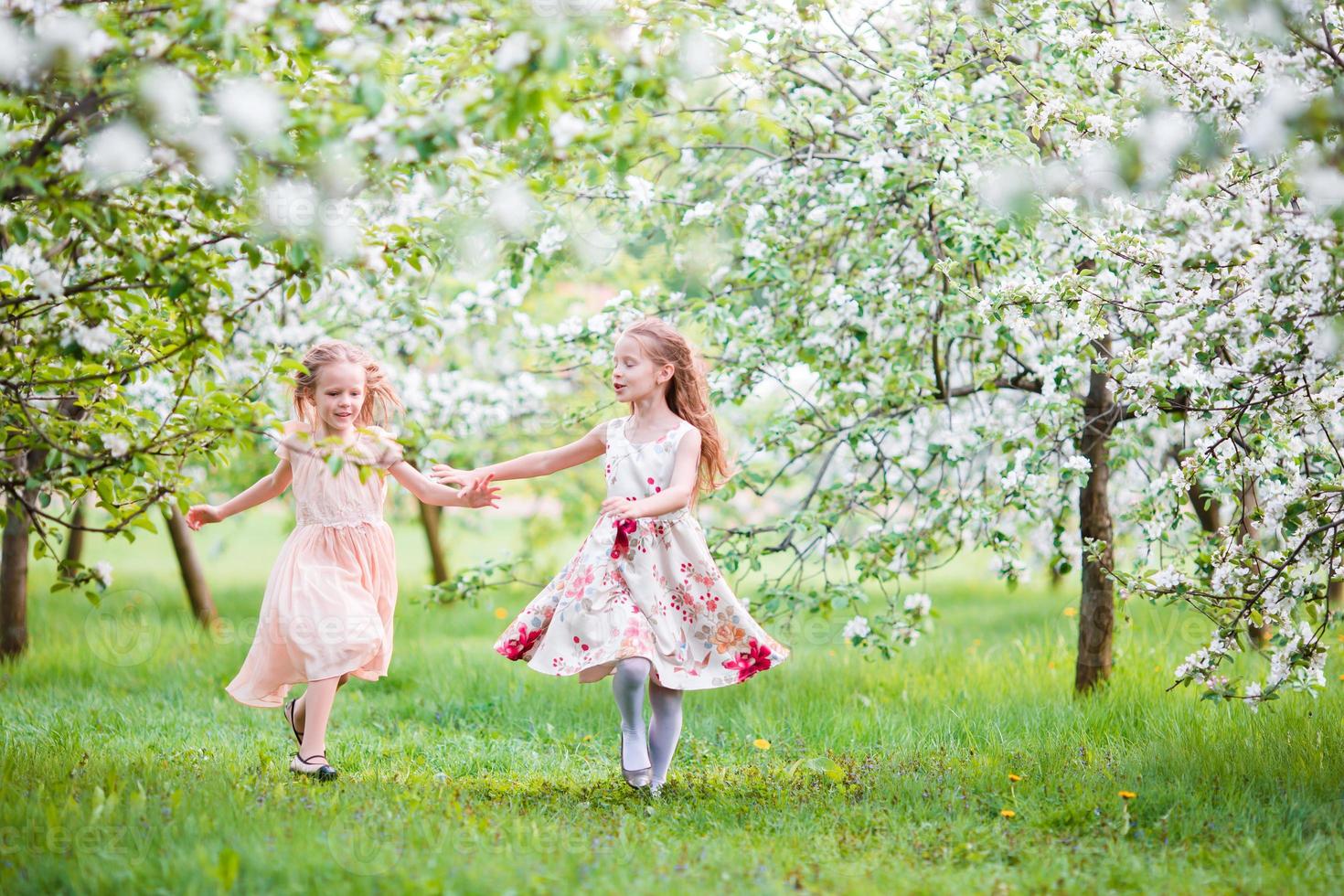 Schöne Mädchen im blühenden Apfelbaumgarten genießen den warmen Frühlingstag foto