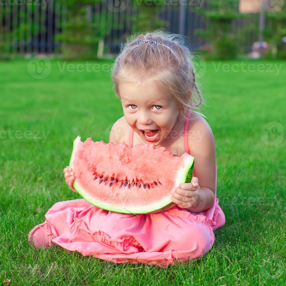 kleines entzückendes mädchen mit einem stück wassermelone in den händen foto