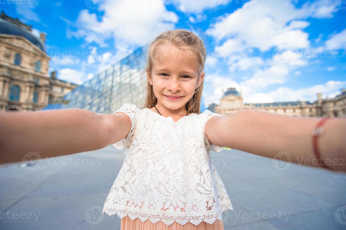 entzückendes kleines mädchen, das selfie mit handy draußen in paris nimmt foto