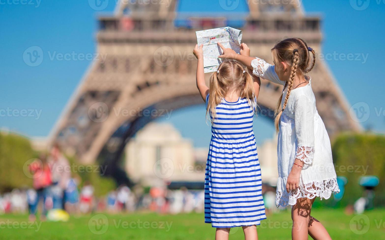 entzückende kleine mädchen mit karte von paris im hintergrund der eiffelturm foto