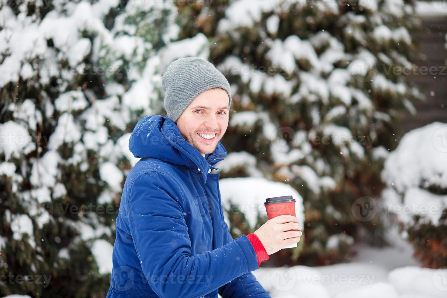 junger kaukasischer mann, der kaffee am gefrorenen wintertag draußen trinkt foto