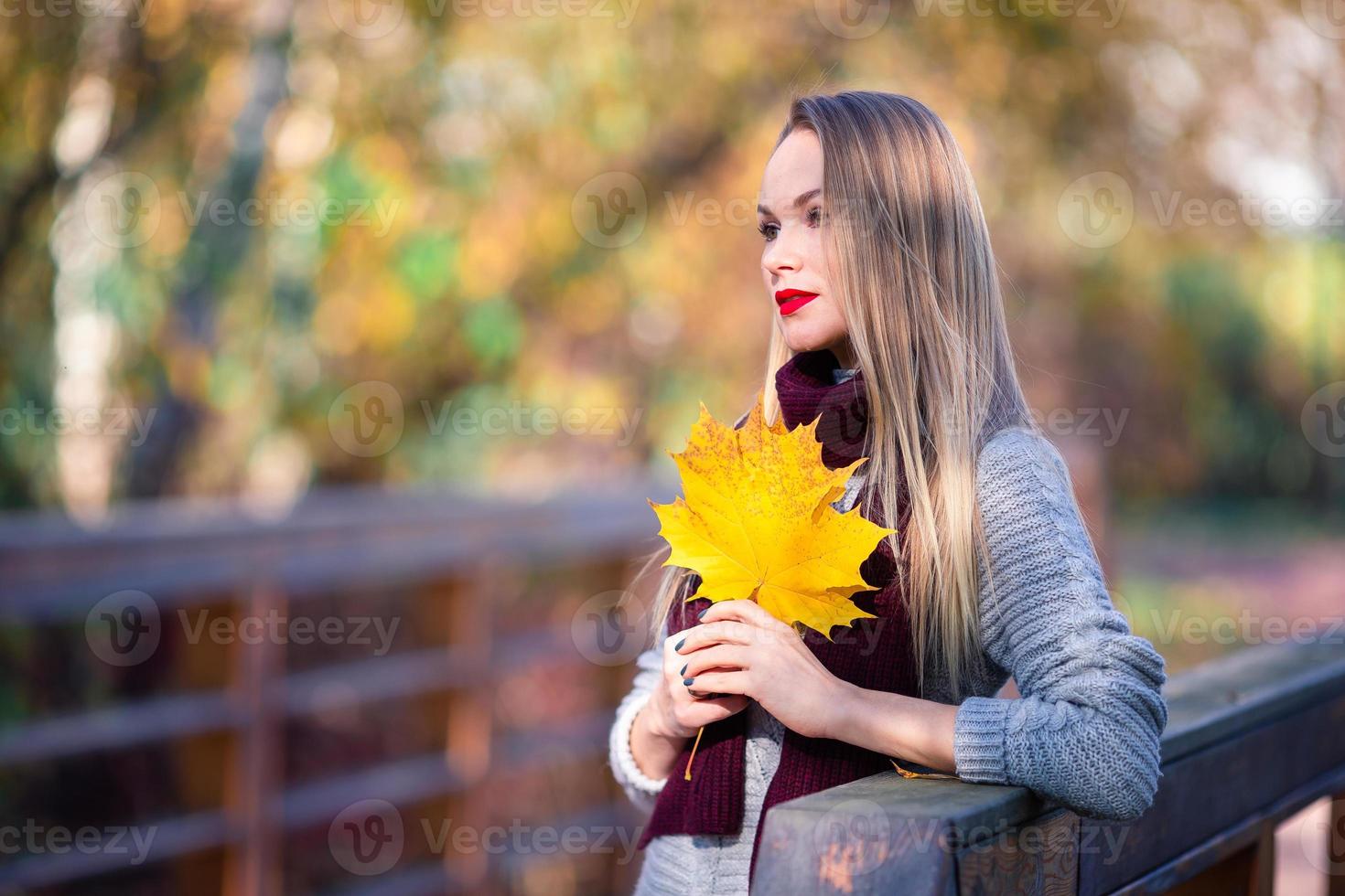 Herbstkonzept - schöne Frau trinkt Kaffee im Herbstpark unter Herbstlaub foto