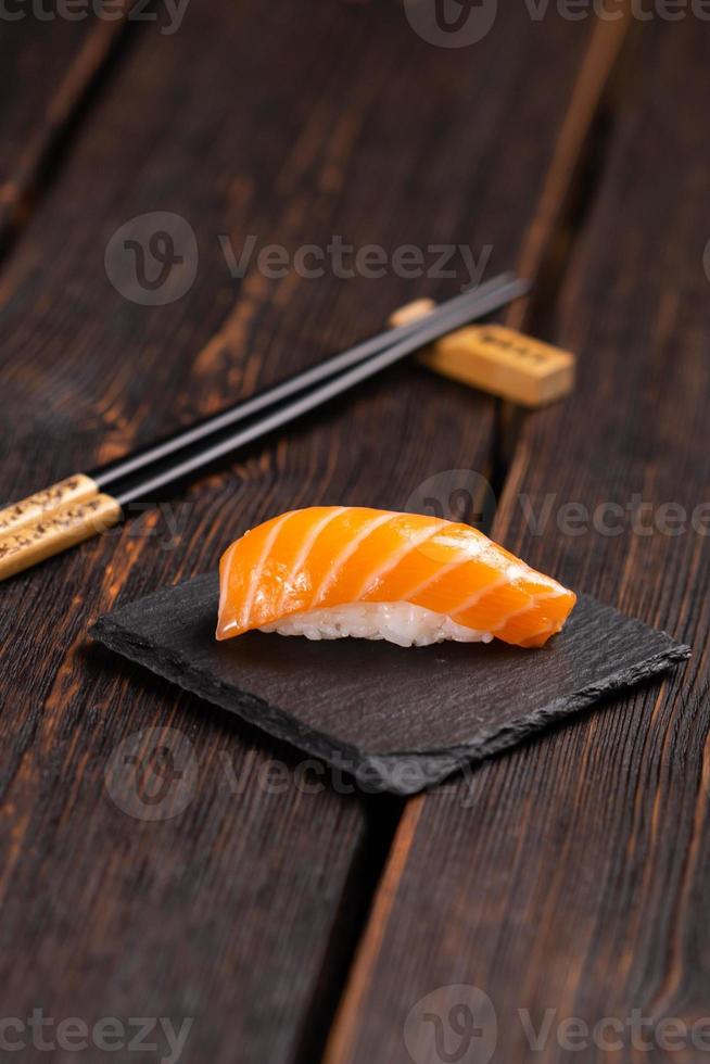 japanisches Sushi-Essen. Sushi-Nigiri mit Lachs auf natürlichem Steinhintergrund mit Holztisch foto