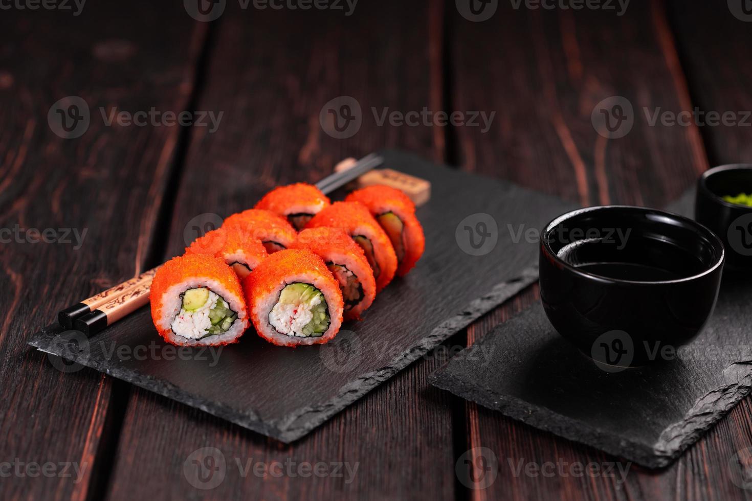 California Sushi Roll mit Krabben, Avocado, Gurke und Tobiko-Kaviar, serviert auf schwarzem Brett, Nahaufnahme - japanisches Essen foto