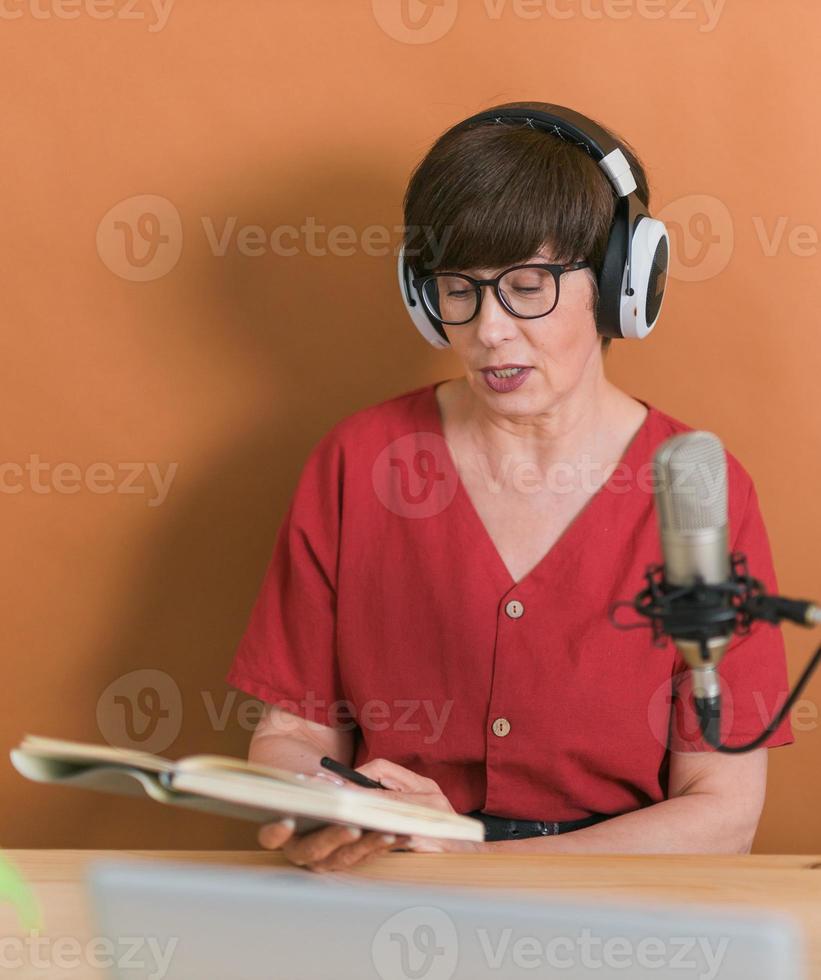 Radiomoderatorin mittleren Alters, die in das Mikrofon spricht und Nachrichten liest - Online-Radiokonzept foto