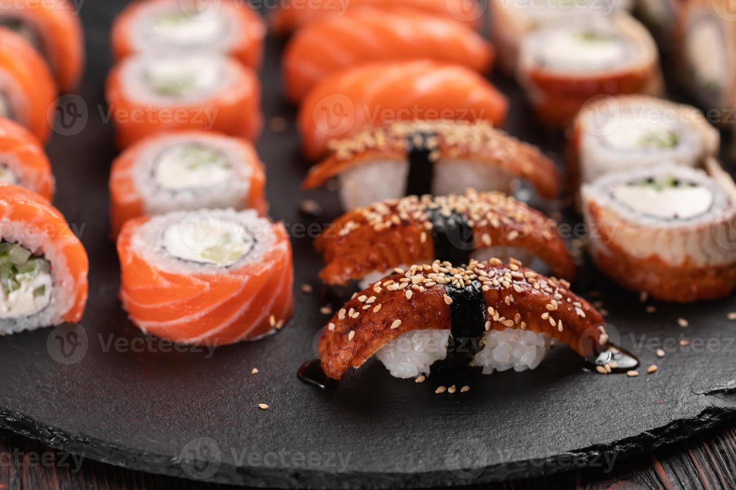 Sushi-Set von oben auf schwarzem Hintergrund Nahaufnahme. eine Auswahl an verschiedenen Maki Nigiri und Brötchen mit Meeresfrüchten und Sojasauce foto