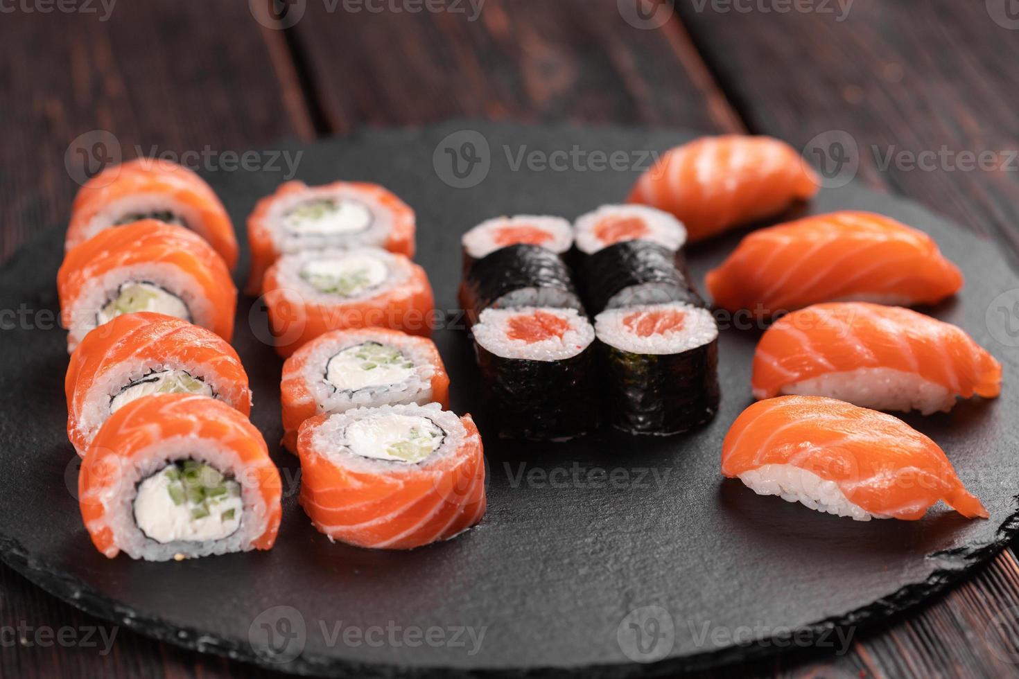 Sushi-Set von oben auf schwarzem Hintergrund Nahaufnahme. eine Auswahl an verschiedenen Maki Nigiri und Brötchen mit Meeresfrüchten und Sojasauce foto