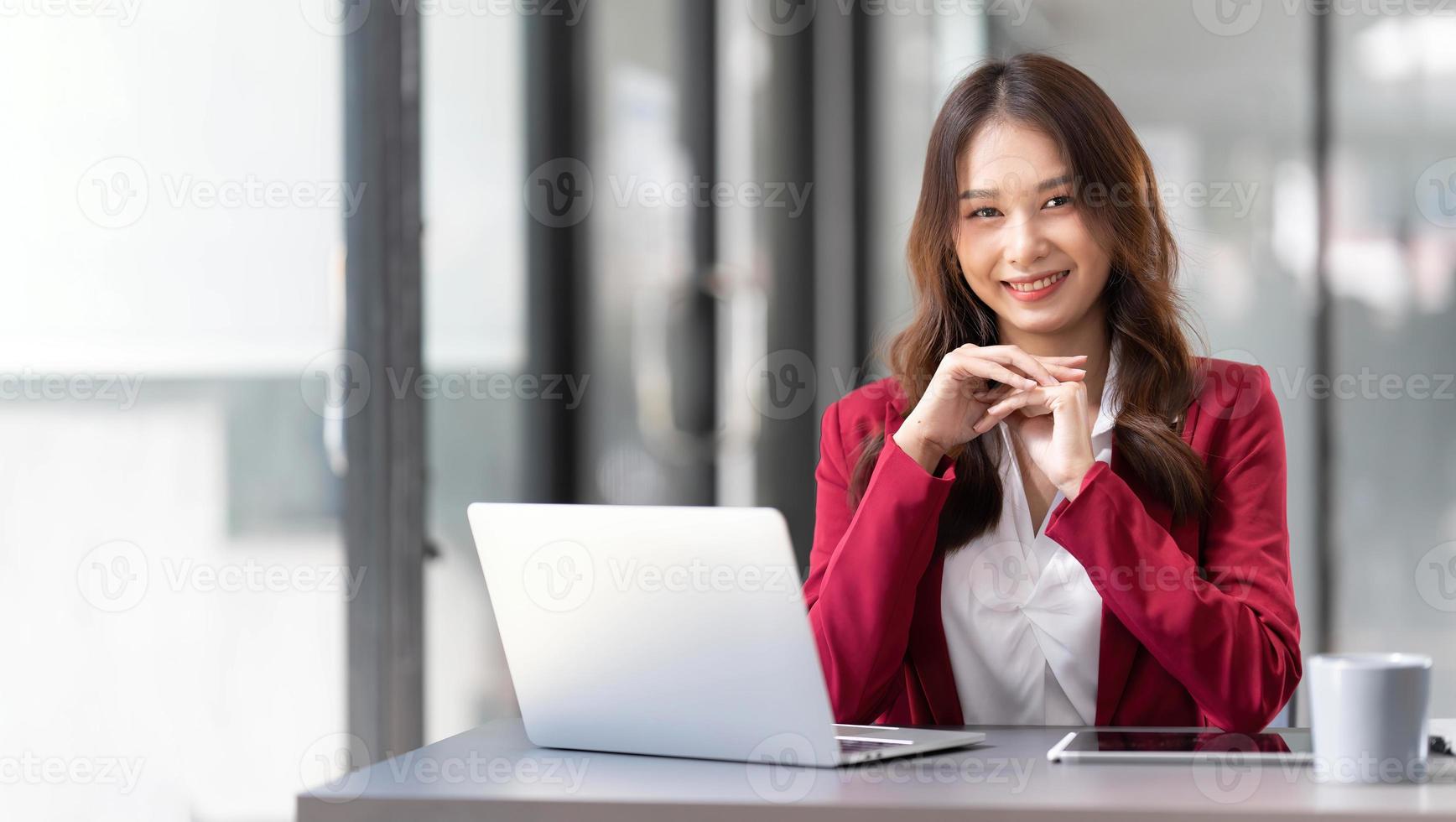 Porträt einer lächelnden, schönen asiatischen Geschäftsfrau im rosafarbenen Anzug, die am Schreibtisch zu Hause mit dem Computer arbeitet. Geschäftsleute Mitarbeiter freiberuflicher Online-Marketing-E-Commerce, Arbeit von zu Hause aus Konzept foto