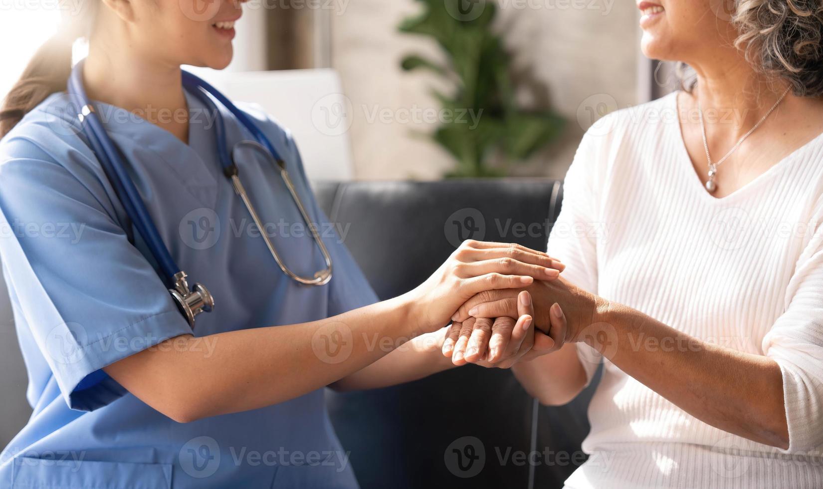 nahaufnahme glücklicher patient hält pflegekraft für eine hand, während er zeit miteinander verbringt. ältere frau im pflegeheim und krankenschwester. foto