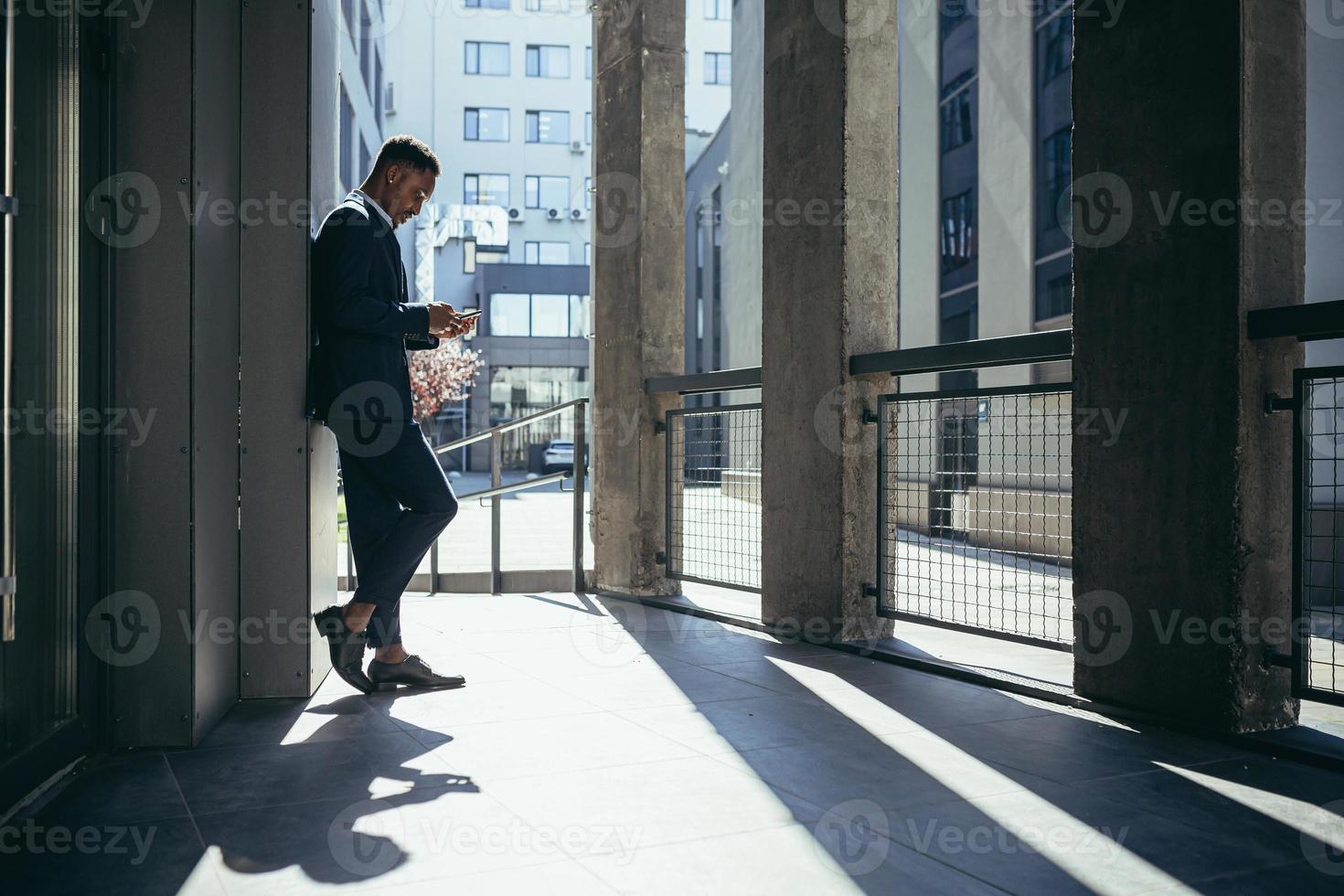 männlicher geschäftsmann in der nähe des büros liest nachrichten vom tablet-computer, afroamerikaner foto