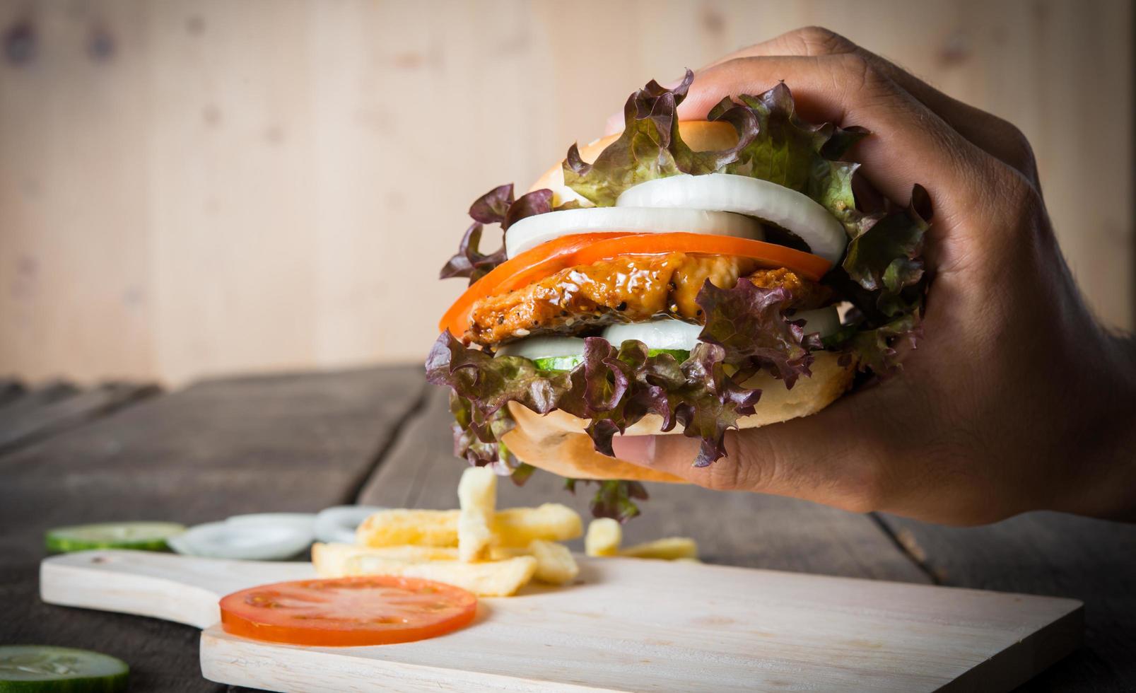 Hände halten Burger über Schneidebrett foto