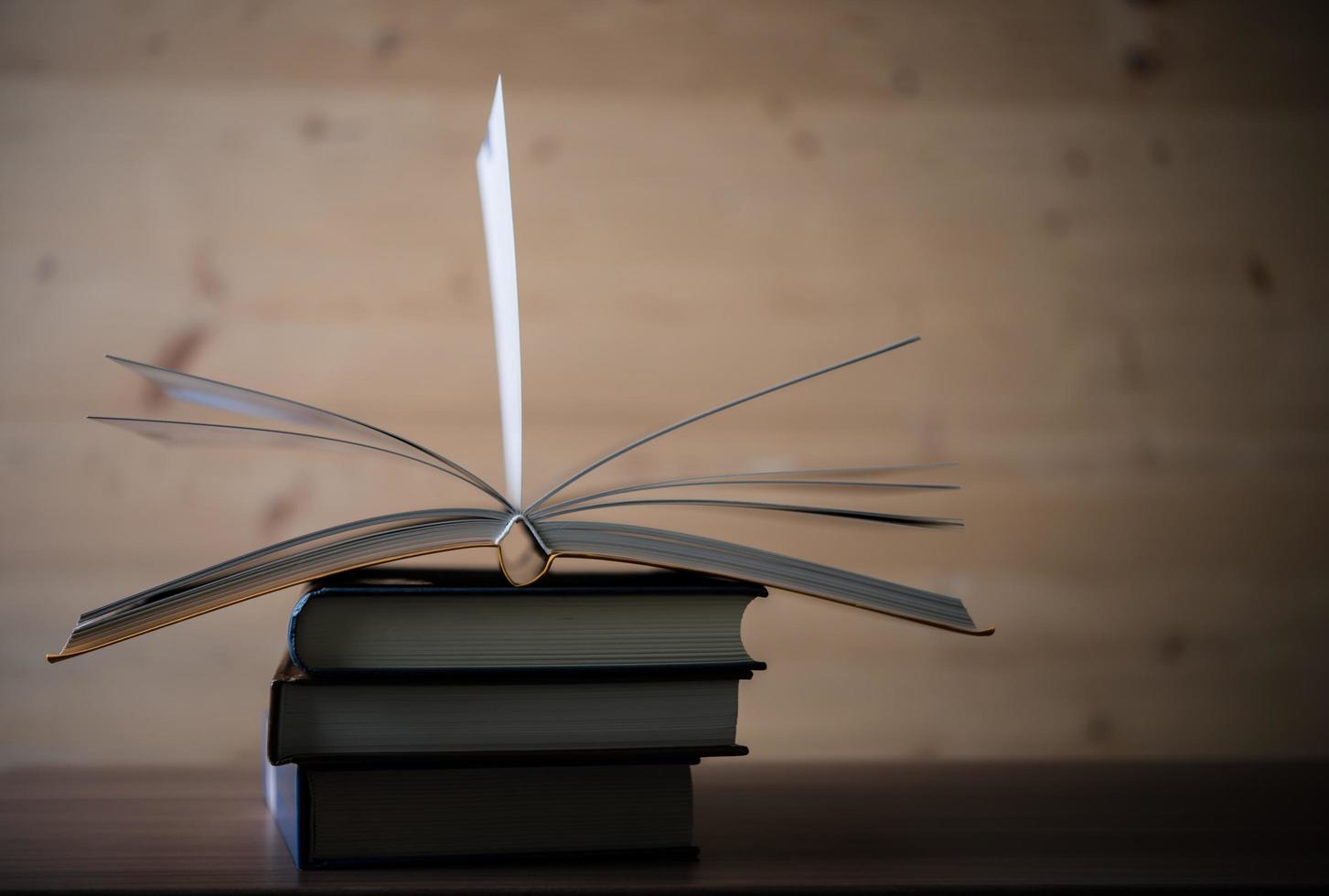 Stapel offener Bücher auf einem Holztisch foto