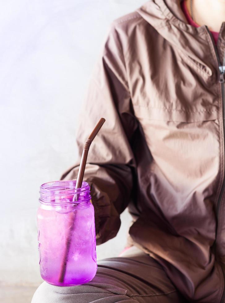 Person hält ein lila Glas im Sitzen foto