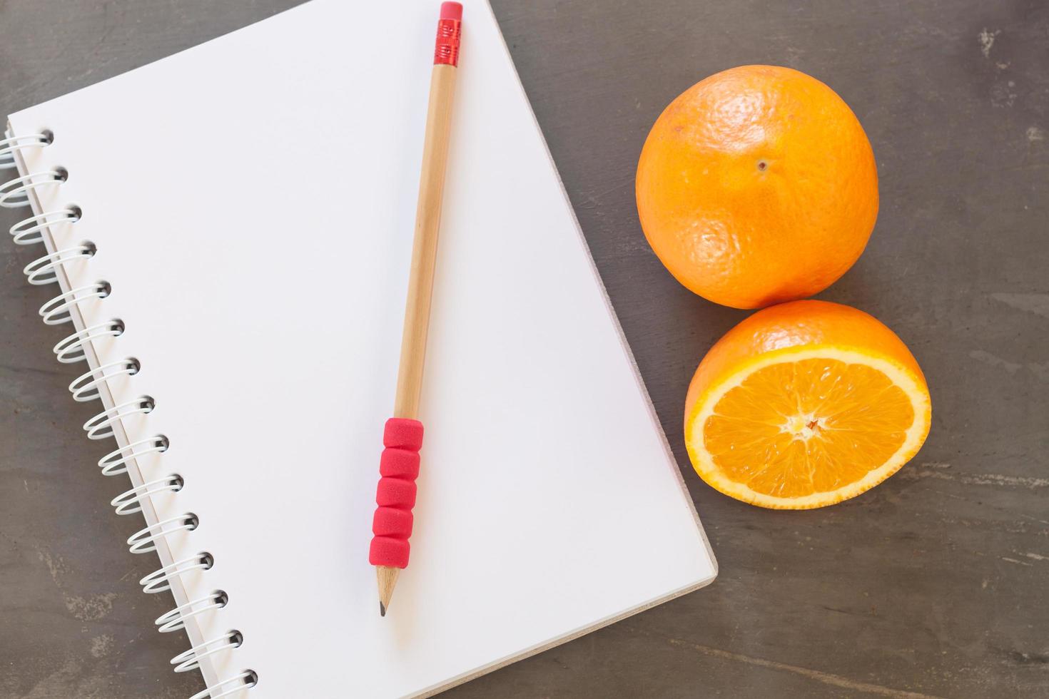 roter Stift auf einem Notizbuch mit Orangen foto