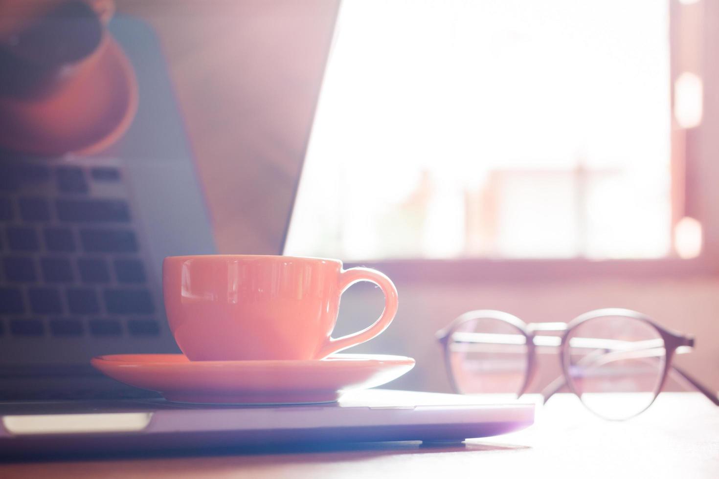 Tageslicht auf einem Laptop mit Kaffeetasse und Gläsern foto