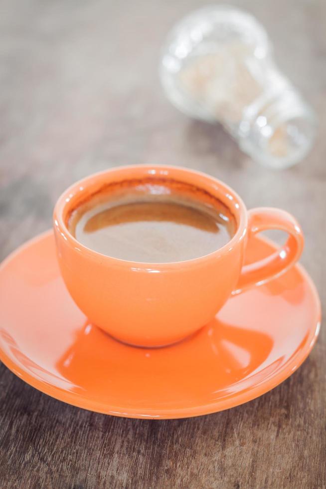 Nahaufnahme einer orange Kaffeetasse auf einem Holztisch foto