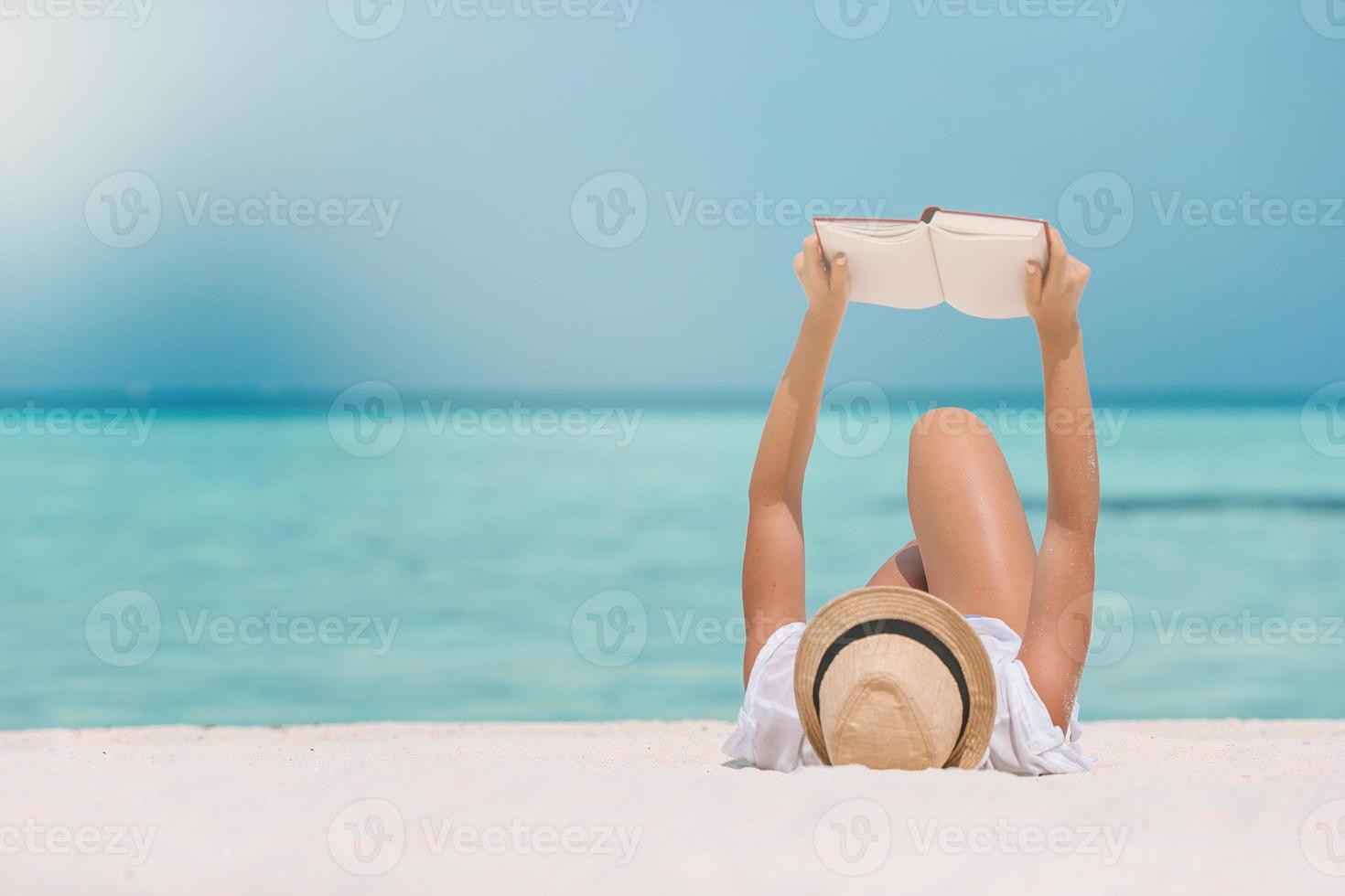 Lesebuch der jungen Frau während des tropischen weißen Strandes foto