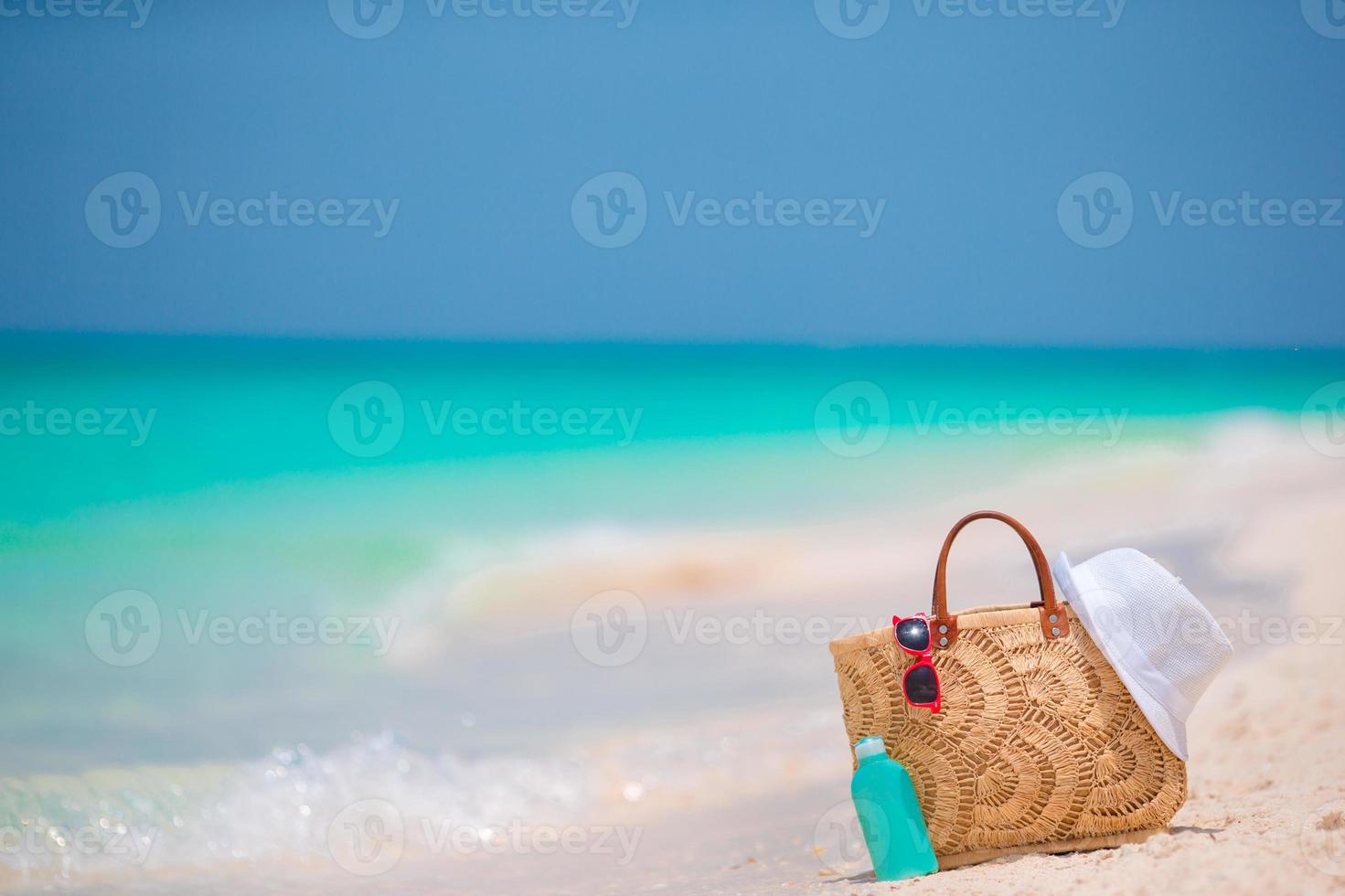 Strandzubehör - Strohsack, weißer Hut und rote Sonnenbrille am Strand foto