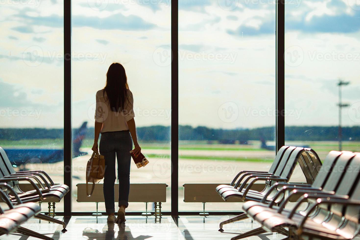 Silhouette einer Fluggastin in einer Flughafenlounge, die auf Flugflugzeuge wartet foto