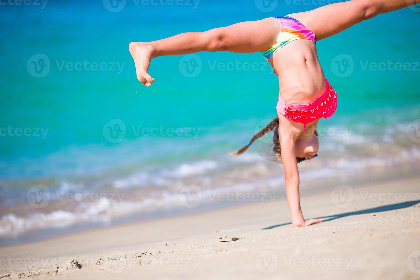 Entzückendes aktives kleines Mädchen am Strand während der Sommerferien foto