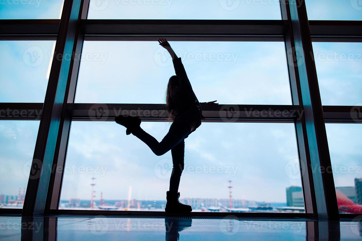 kleines Mädchen im Flughafen in der Nähe des großen Fensters, während es auf das Boarding wartet foto