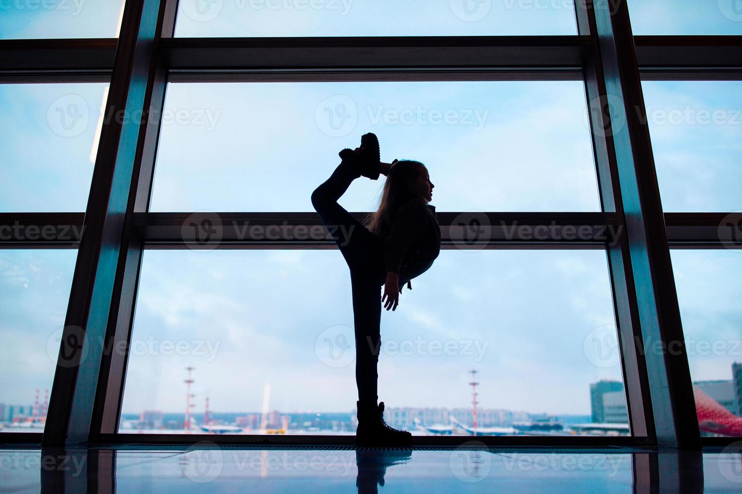 kleines Mädchen im Flughafen in der Nähe des großen Fensters, während es auf das Boarding wartet foto