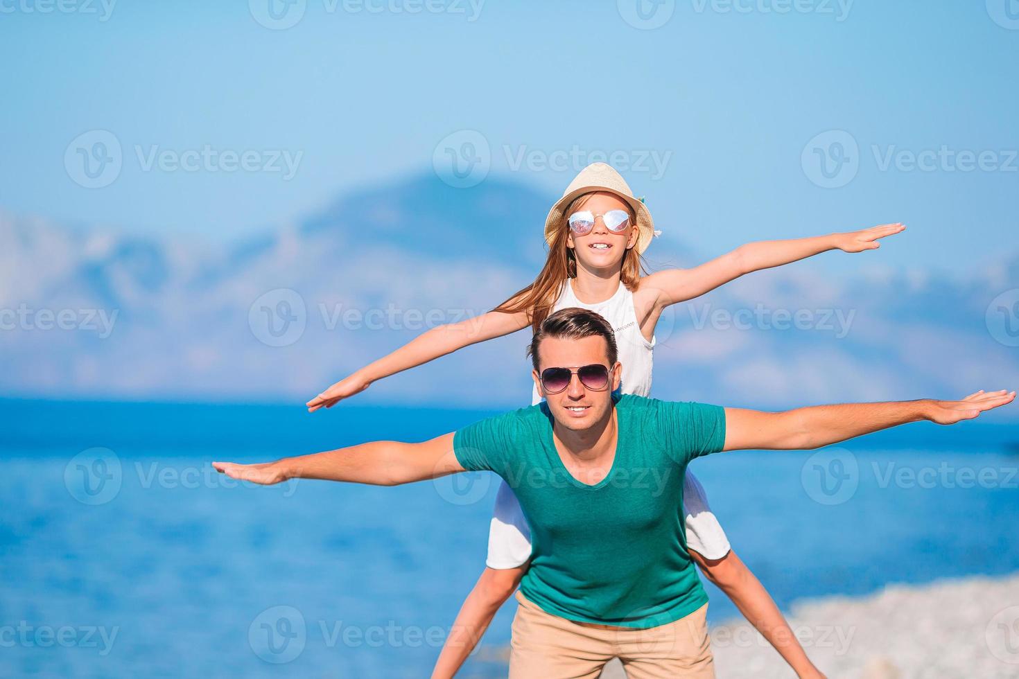 kleines mädchen und glücklicher vater, der spaß während des strandurlaubs hat foto