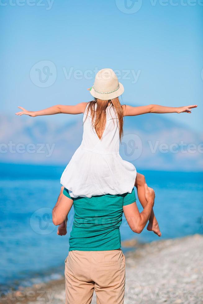 kleines mädchen und glücklicher vater, der spaß während des strandurlaubs hat foto