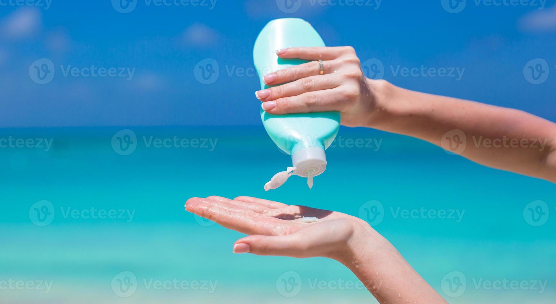 Frauenhände, die Sonnencreme aus der Sonnencremeflasche auftragen foto