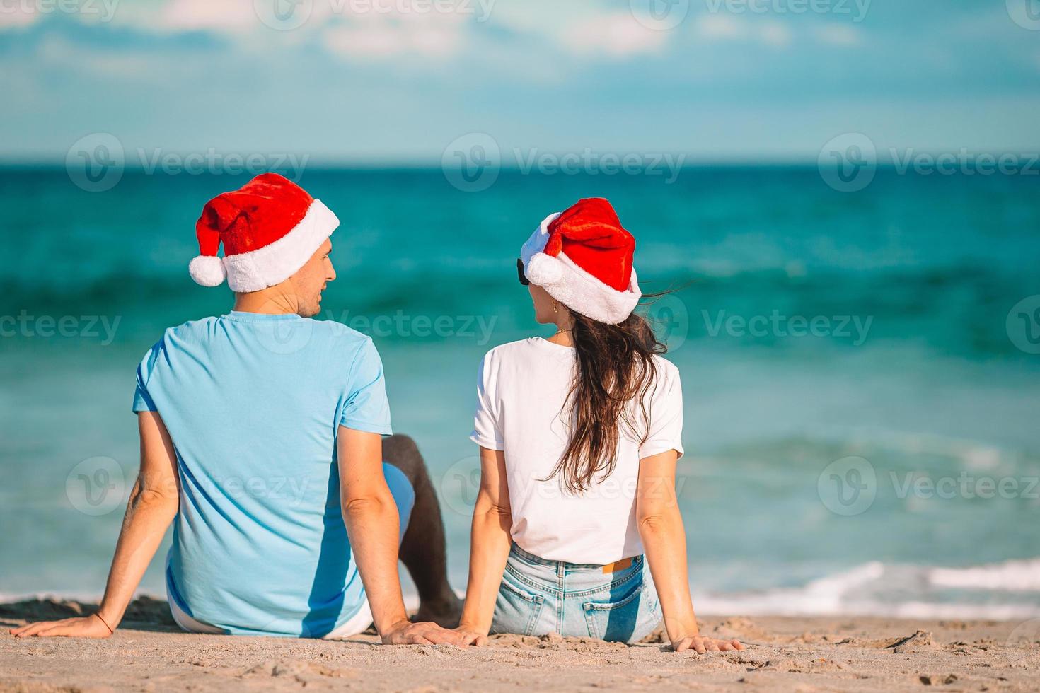 Weihnachtsglückliches Paar in Weihnachtsmützen im Strandurlaub foto