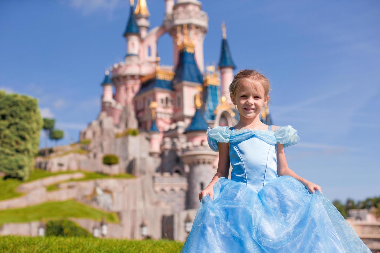 Kleines entzückendes Mädchen im Aschenputtelkleid im märchenhaften Disneyland Park foto