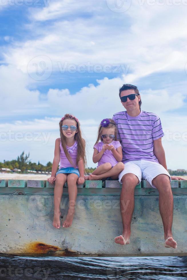 Dreiköpfige Familie auf Holzsteg mit Meerblick foto