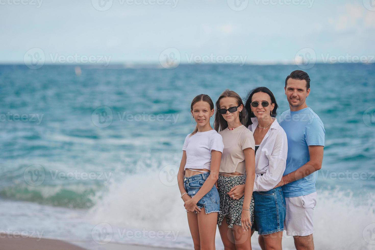 glückliche familie, die während der sommerferien am strand posiert foto