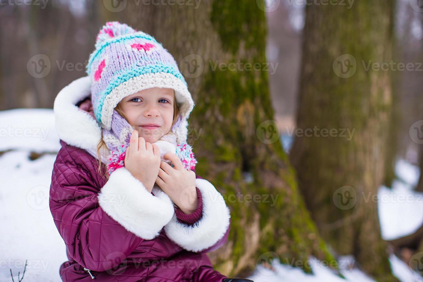 Porträt des kleinen glücklichen Mädchens am sonnigen Wintertag des Schnees foto